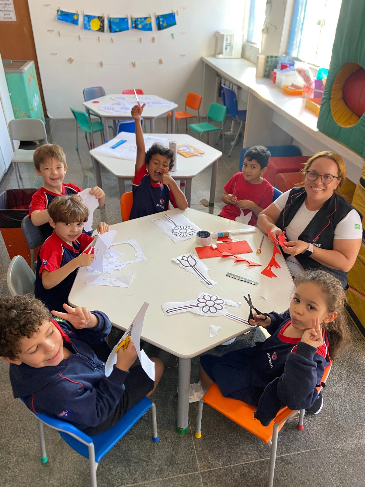 Crianças da Aussie Education em atividade de artes, recortando flores de papel.