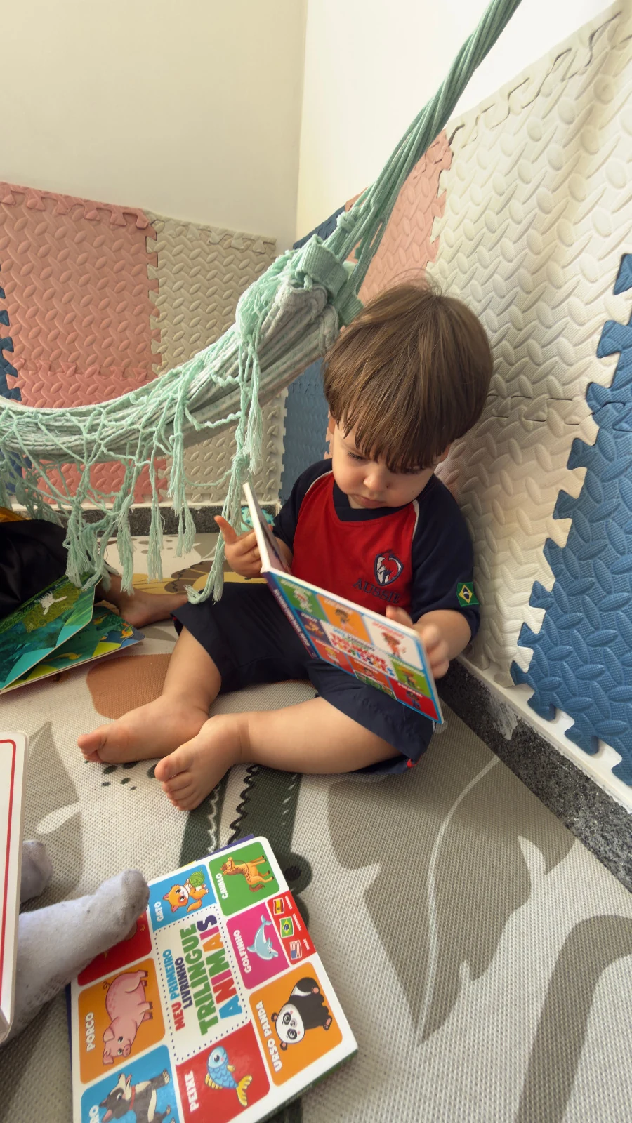 Criança da Aussie Education lendo um livro tranquilamente em uma rede.